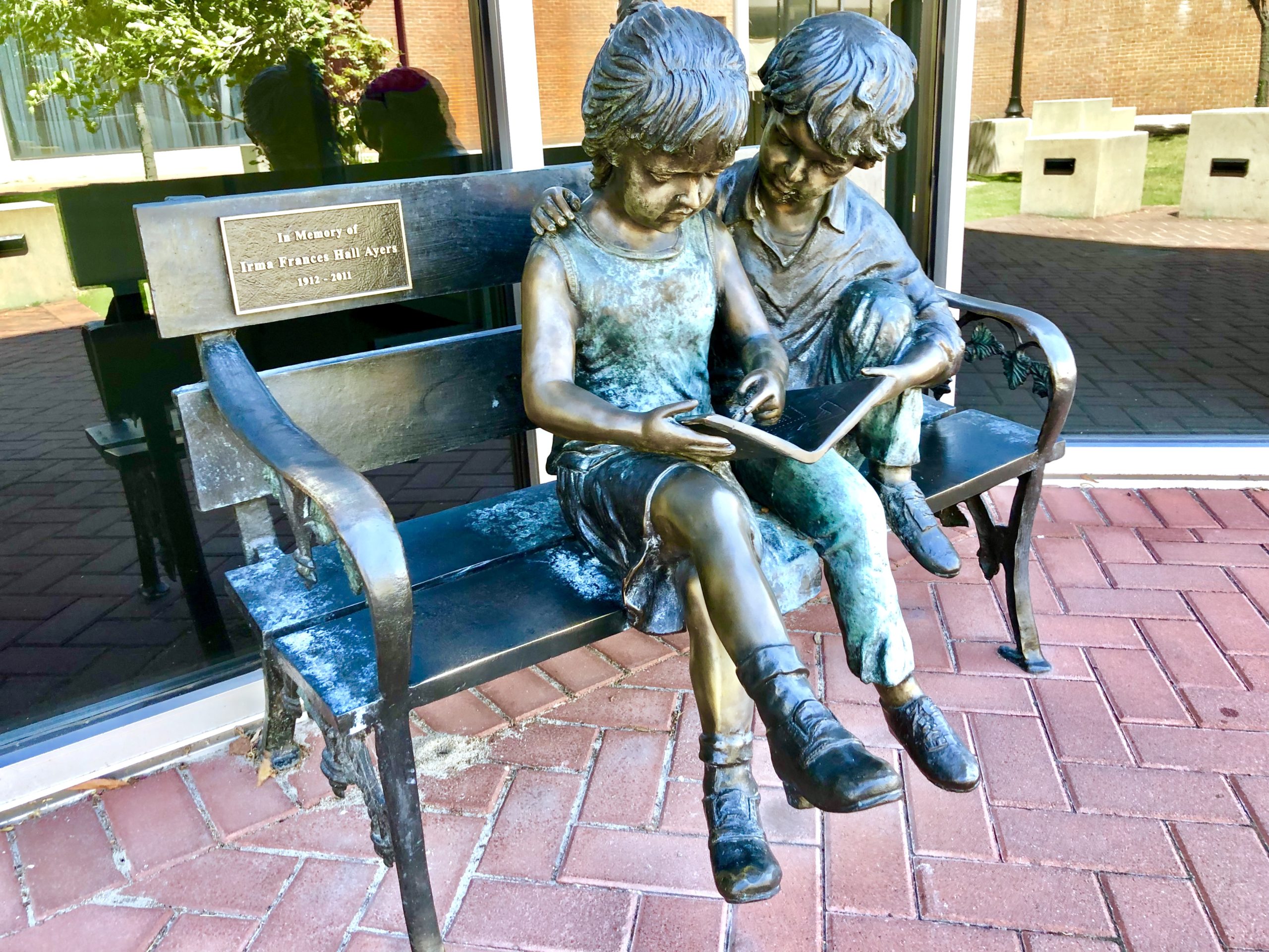Bronze statue of two kids on a bench reading