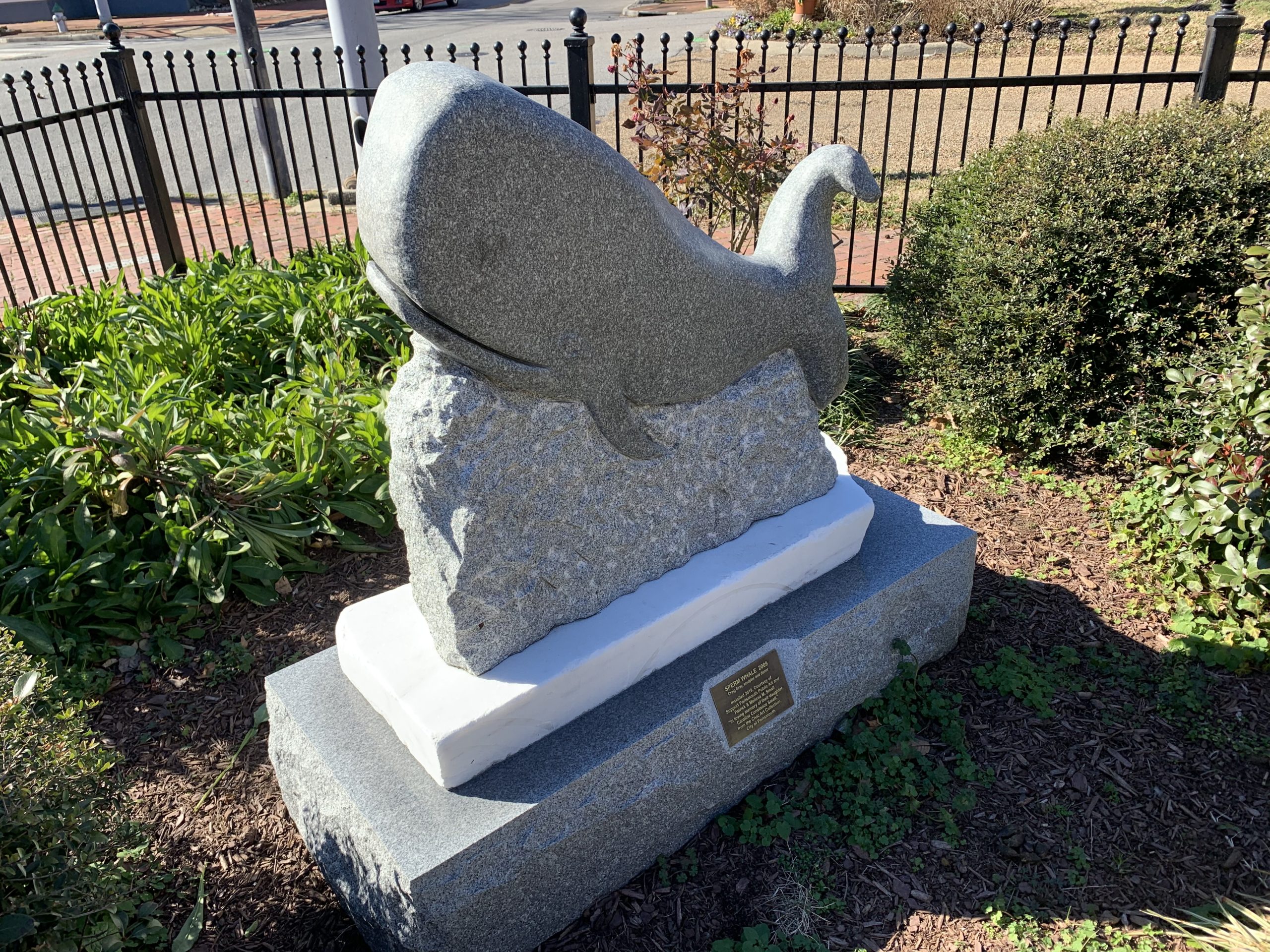 Concrete statue of sperm whale in park setting