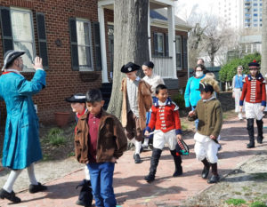 Costume Character leading group of young reenactors on a tour of Olde Towne Portsmouth Virginia