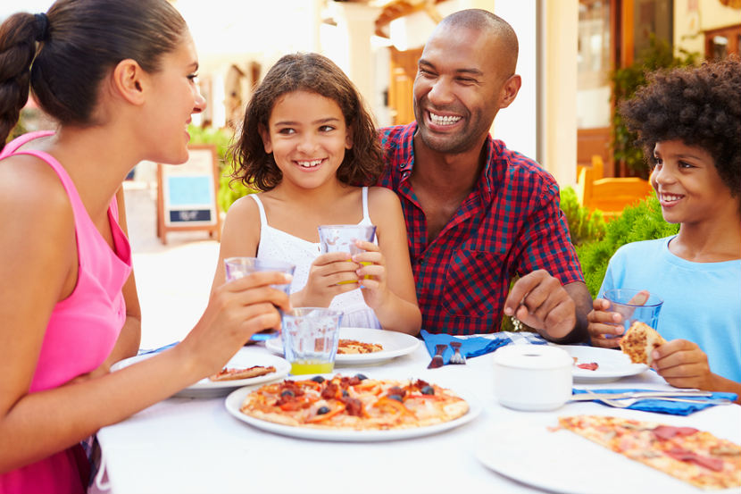 Family of four at a table eating pizza outdoor